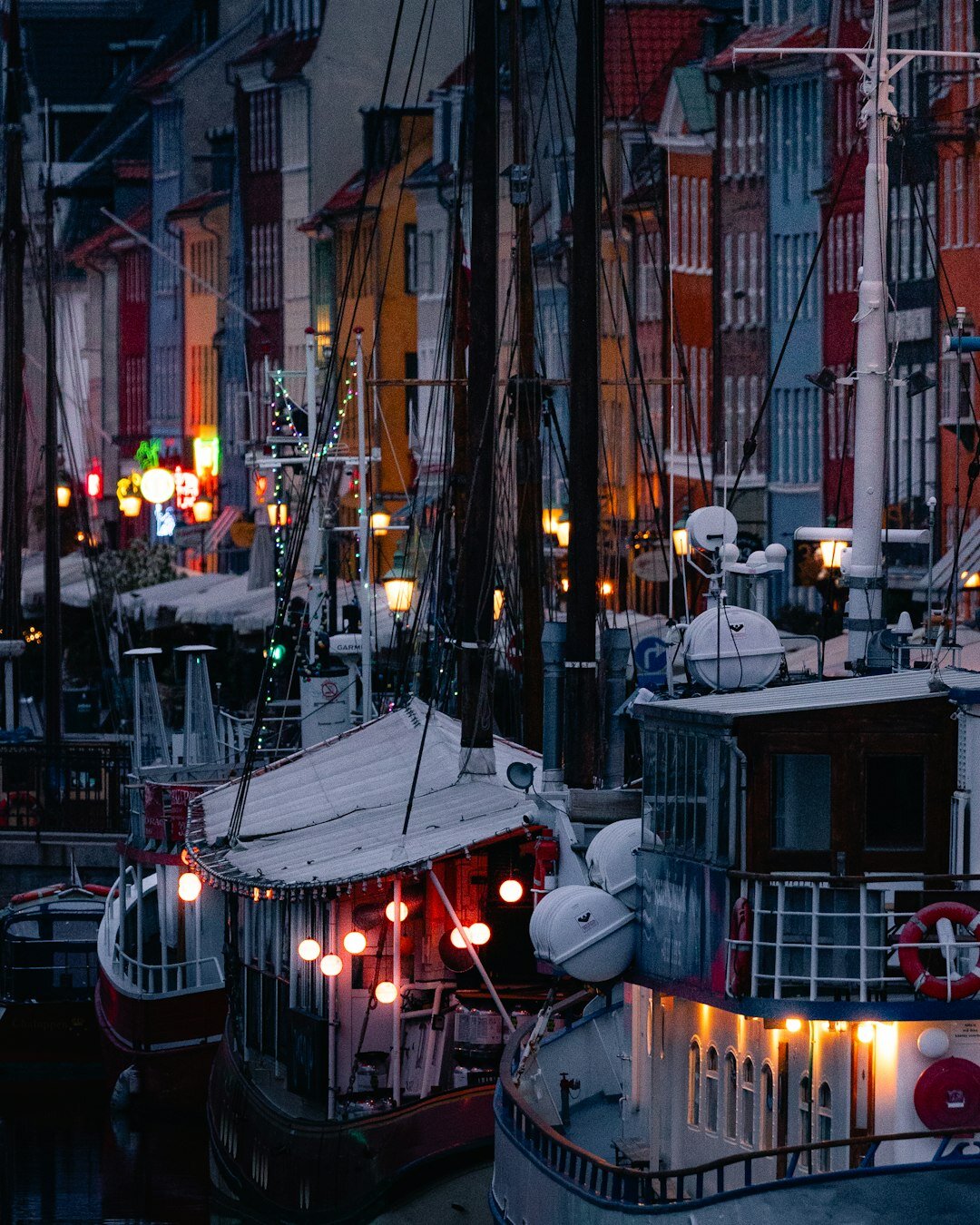 Old wooden fishing boats docked in a quiet Danish harbour at dusk